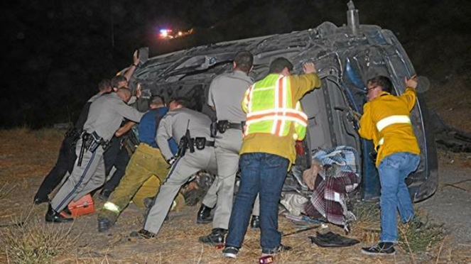 CHP officers, LAPD officers and paramedics held up a vehicle to rescue a trapped driver who was screaming for help after a rollover crash on Sept. 16, 2014. (Credit: Rick McClure, RMc Video)